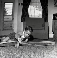 Boy playing with a toy car on the floor poster print