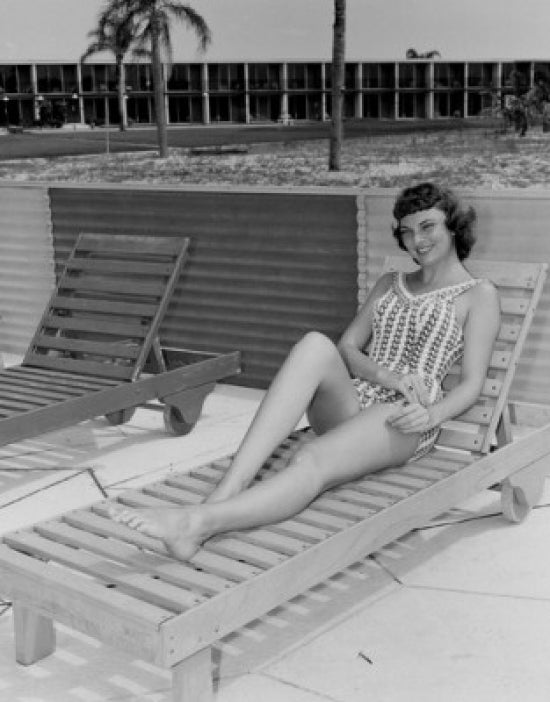 Poster print of a beautiful young woman smiling while sitting on a lounge chair.