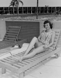 Poster print of a beautiful young woman smiling while sitting on a lounge chair.