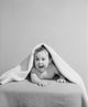 Portrait of a baby boy lying under cover on bed poster print.