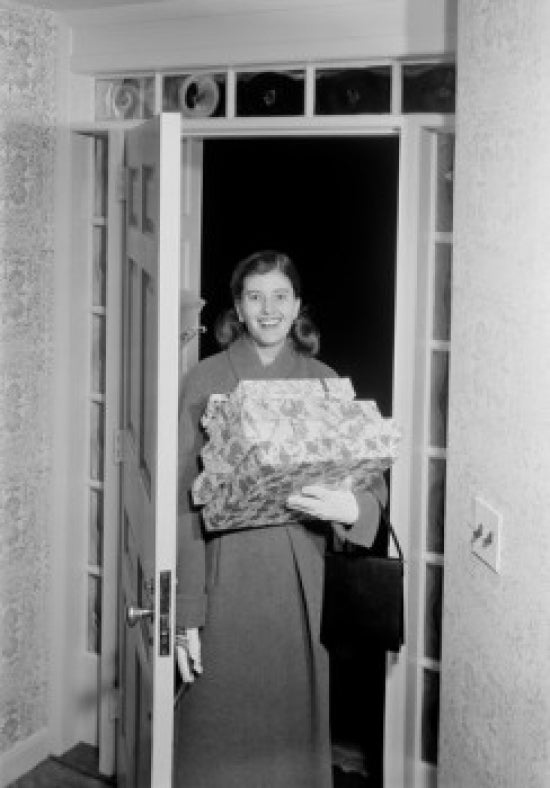 Woman carrying Christmas presents in doorway poster print