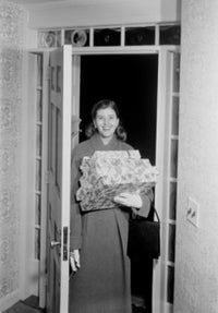 Woman carrying Christmas presents in doorway poster print