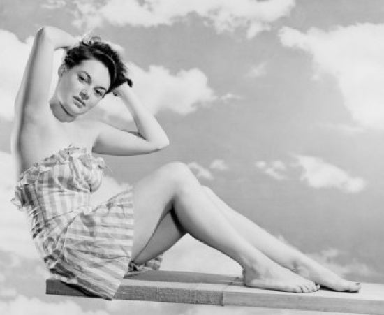 Portrait of young woman in swimsuit sitting on diving board poster print
