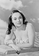 Portrait of a young woman in swimsuit lying on diving board