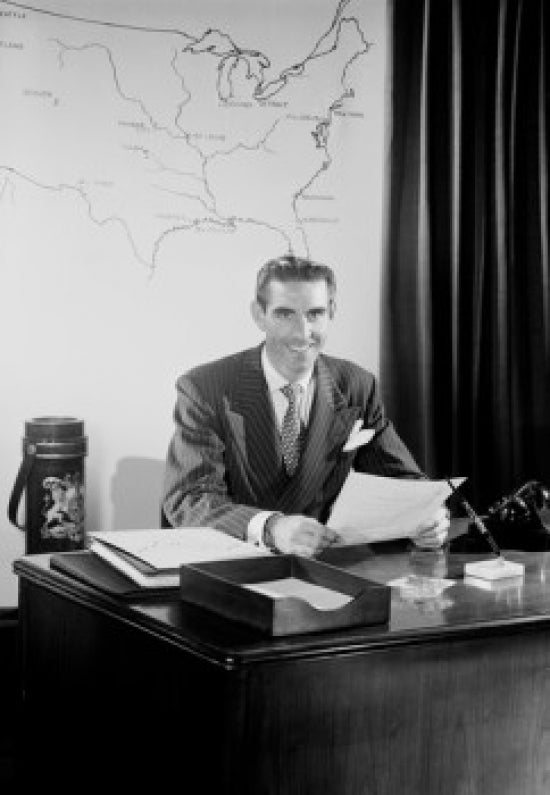 Mid adult man sitting at desk in office poster print