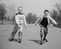Poster print of two boys roller skating in a park.