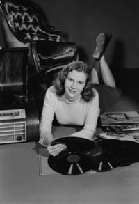 Studio portrait of a young woman with records poster print.