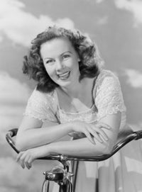 Portrait of a young woman with a bicycle against a cloudy sky