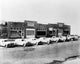 Trucks in front of Alban Tractor Co factory poster print, showcasing vintage industrial scene.