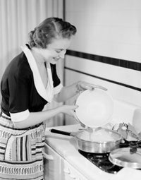 Poster print of a happy young woman making an omelet in a kitchen setting.