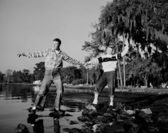 Young couple standing on pebble at lakeshore poster print