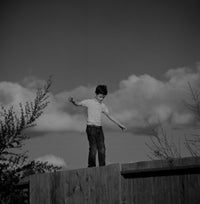 Boy Balancing on Fence Poster Print showcasing playful childhood spirit.