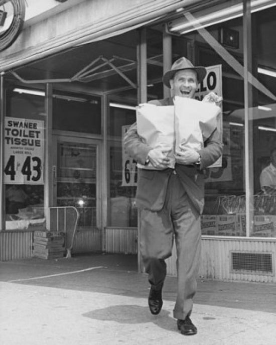 Mid adult man carrying shopping bags in front of a store poster print.