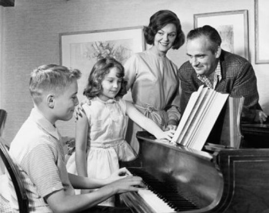 Side profile of a boy playing piano with family standing beside him poster print.