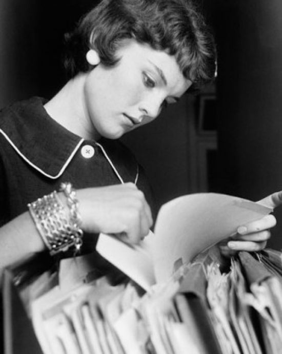 Close-up of a businesswoman searching for files in a filing cabinet poster print.