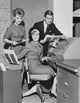 Poster print featuring two businesswomen and a businessman working on an accounting machine.