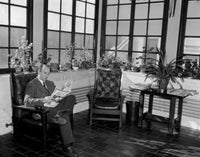 Man sitting in room reading newspaper poster print