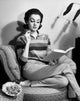 Young woman sitting on an armchair reading a book poster print.