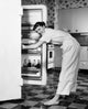 Poster Print of a young woman standing in front of a refrigerator