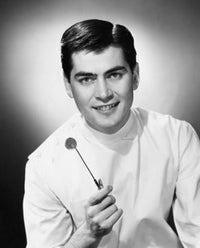 Portrait of a male dentist holding an angled mirror and smiling