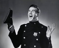 Portrait of a police officer holding a uniform cap and laughing.