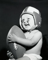 Close-up of a baby boy holding a football, charming poster print.