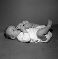 Adorable baby girl lying on back sucking toes poster print.