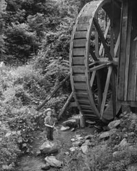 Boy fishing in a stream near a water wheel in North Carolina, USA - Poster Print