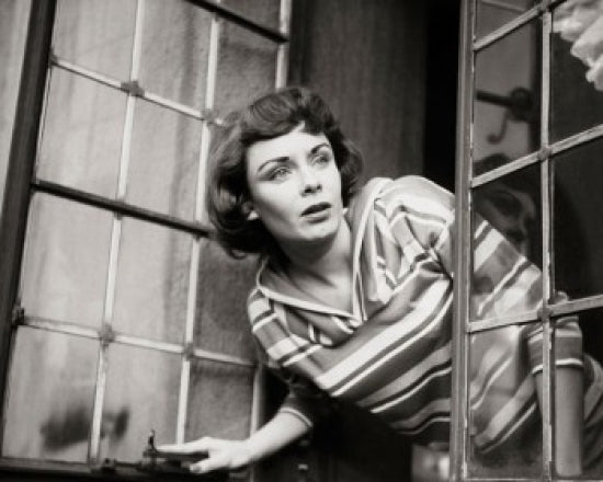 Close-up of a young woman peeking through a window poster print