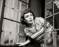 Close-up of a young woman peeking through a window poster print