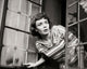 Close-up of a young woman peeking through a window poster print