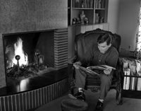 Man sitting in armchair by fireplace poster print