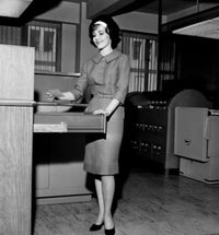 Businesswoman holding a card by a filing cabinet poster print