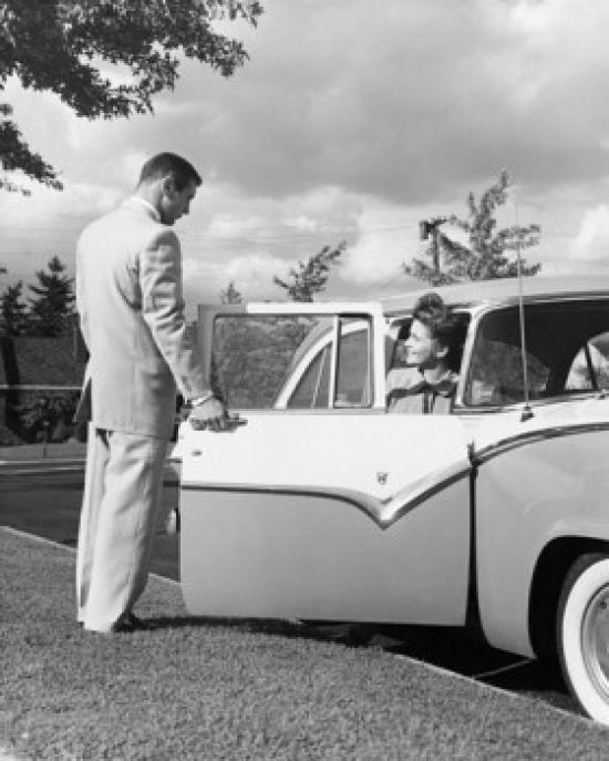 Young man opening car door for teenage girl poster print