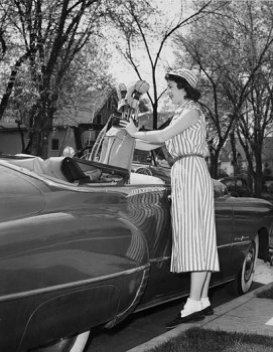 Young woman putting a golf bag in a car poster print.