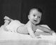 Adorable baby lying on a blanket and smiling poster print.