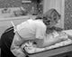 Mother bending over baby lying on changing mat poster print