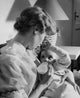 Poster print of a young woman feeding her baby with a baby bottle.