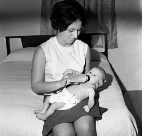 Mother Feeding Baby with Bottle Poster Print showcasing a tender moment.