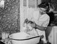 Art print of a young woman washing her son in a bathtub.
