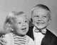 Close-up poster print of a smiling boy and his sister.