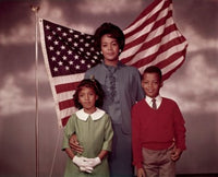 Family standing in front of an American flag poster print.