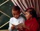 Close-up poster print of a boy reading a book with his sister.