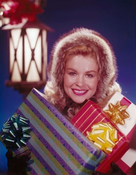 Portrait of a mature woman holding Christmas presents and smiling.
