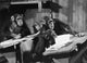 Four chimpanzees sitting in a classroom poster print.