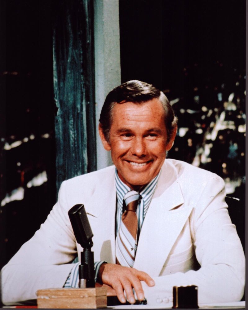 Johnny Carson sitting at desk in white suit photo print
