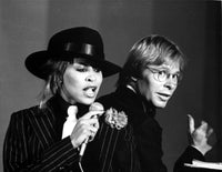 Photo print of John Denver and Tina Turner performing together.