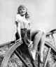 Gene Tierney sitting on a giant wooden wheel photo print.