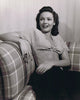 Gene Tierney sitting back on a patterned couch photo print