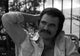Burt Reynolds iconic photo print wearing unbuttoned shirt with hand on head.